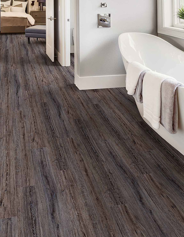 Close up image of a trending 2020 floors utilizing luxury vinyl tiles (LVT) and a large white soaking tub.